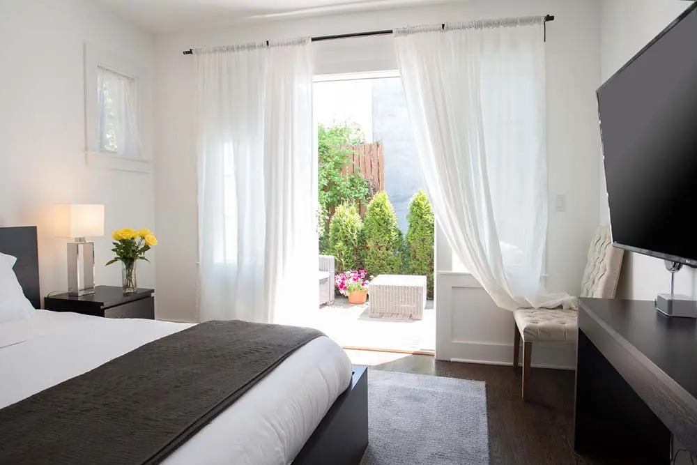 bedroom with TV with doors leading outside to patio