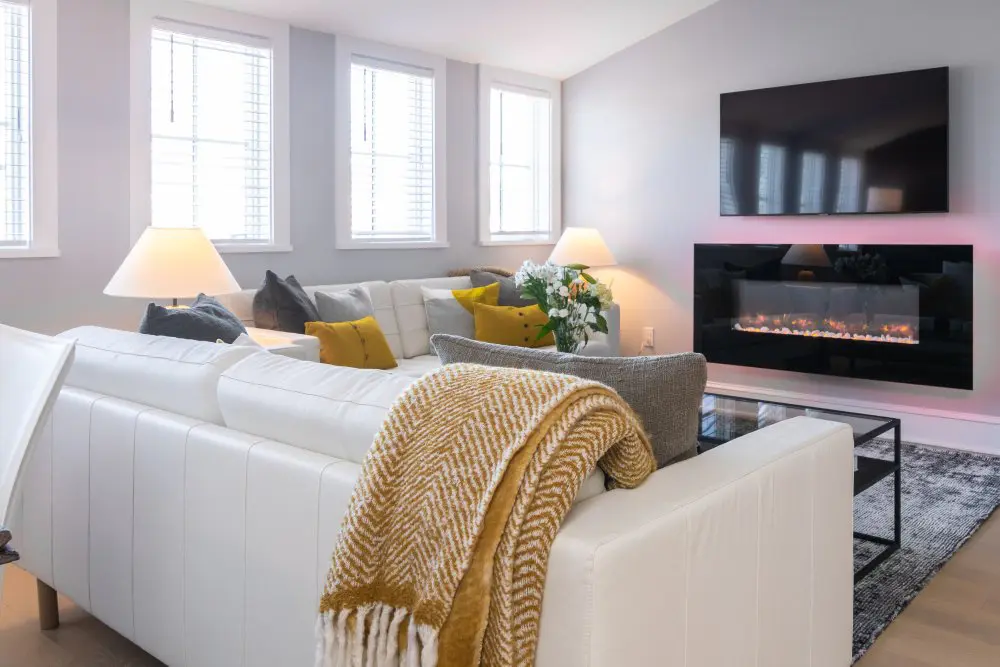 Cozy fireplace with tv above and couches surrounding.