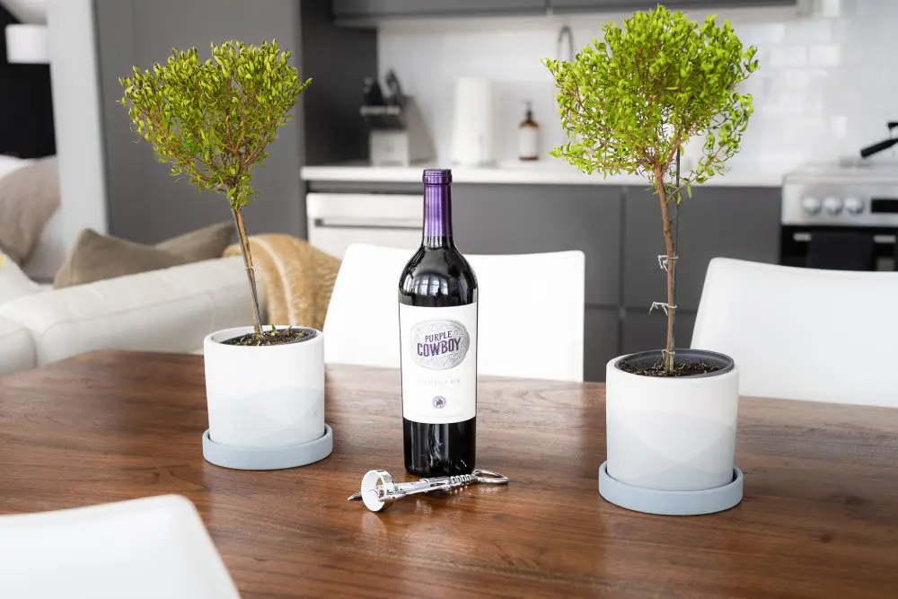 Bottle of purple cowboy wine sits atop a kitchen table.